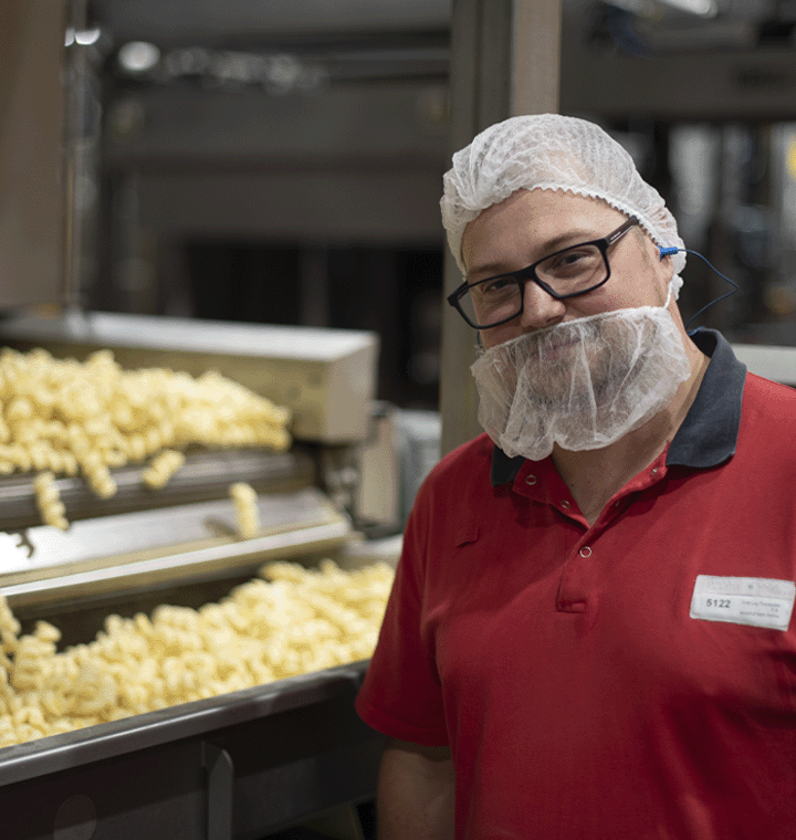 Man wearing personal protective equipment next to PepsiCo product in a plant