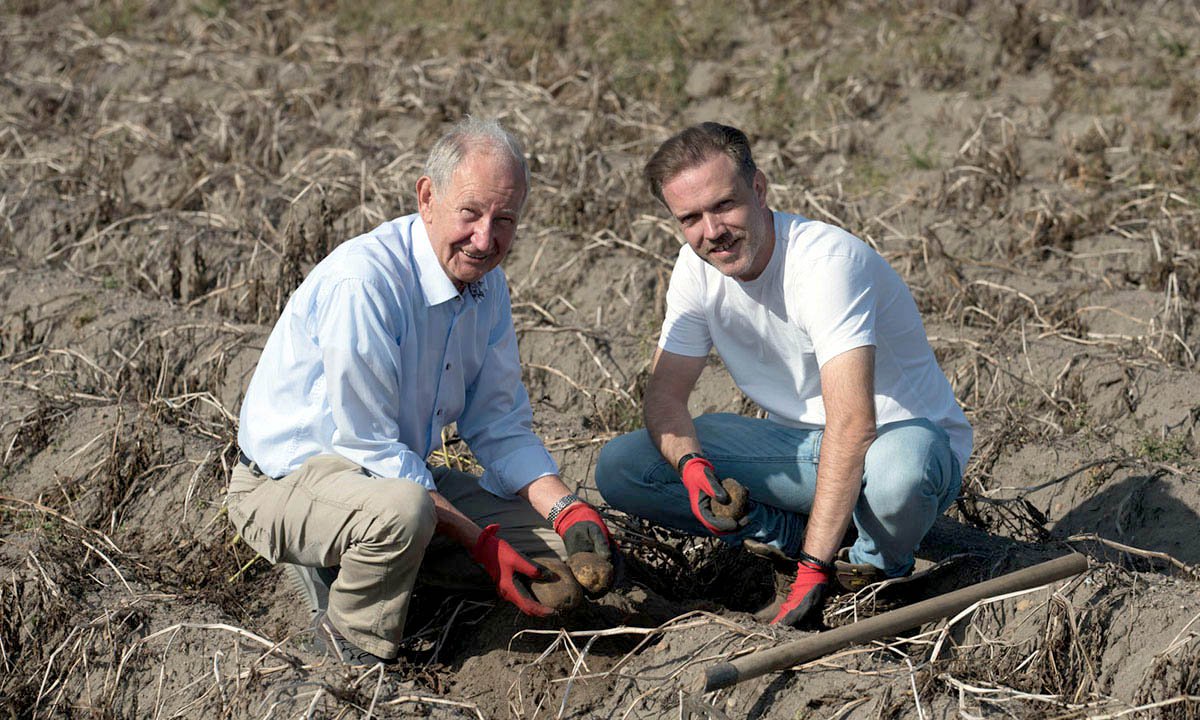 An associate and a farmer inspect farmland