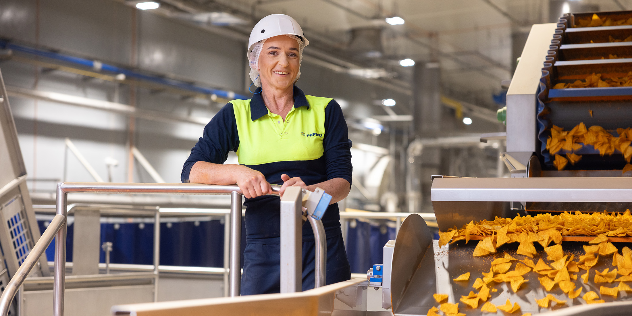 Female associate smiling next to a chip machine in a manufacturing plant