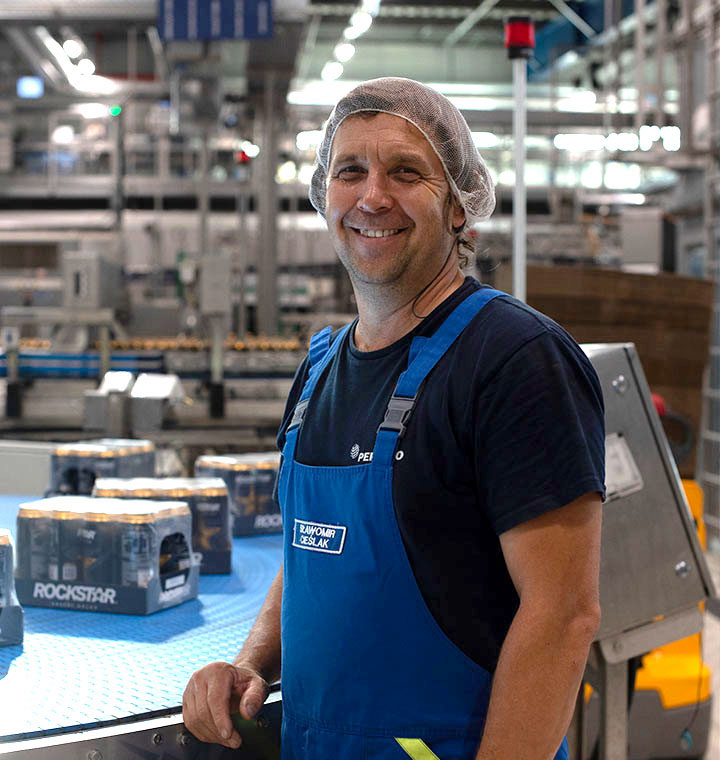 Male associate standing next to machinery in a manufacturing plant