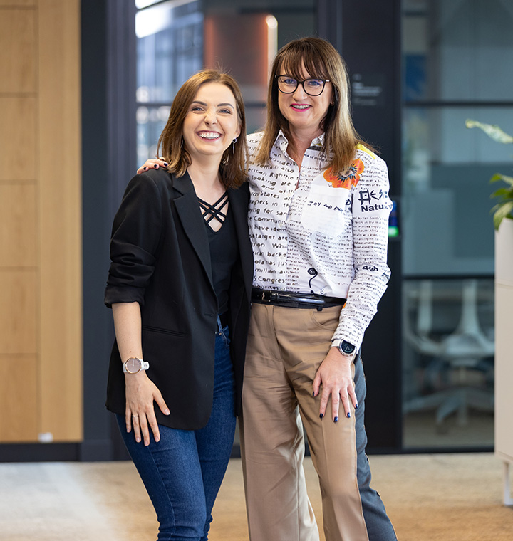 Two female associates hugging in an office