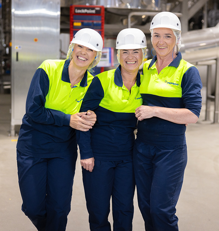 Female associates hugging in a manufacturing plant