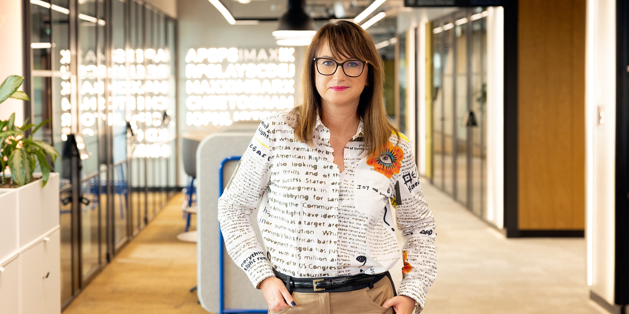 Female associate standing with hands in pockets in an office