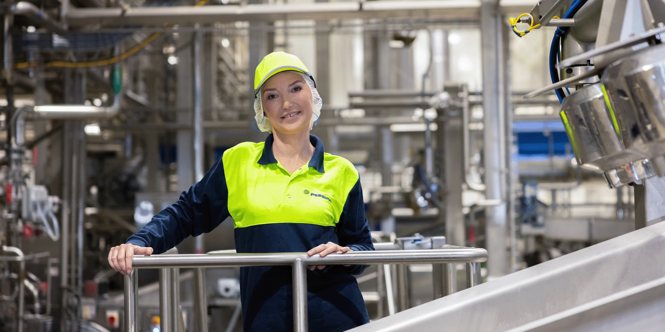 Associate standing next to manufacturing plant machinery