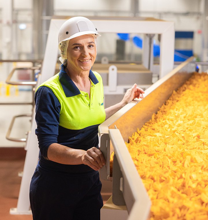 Associate standing next to chip conveyor belt