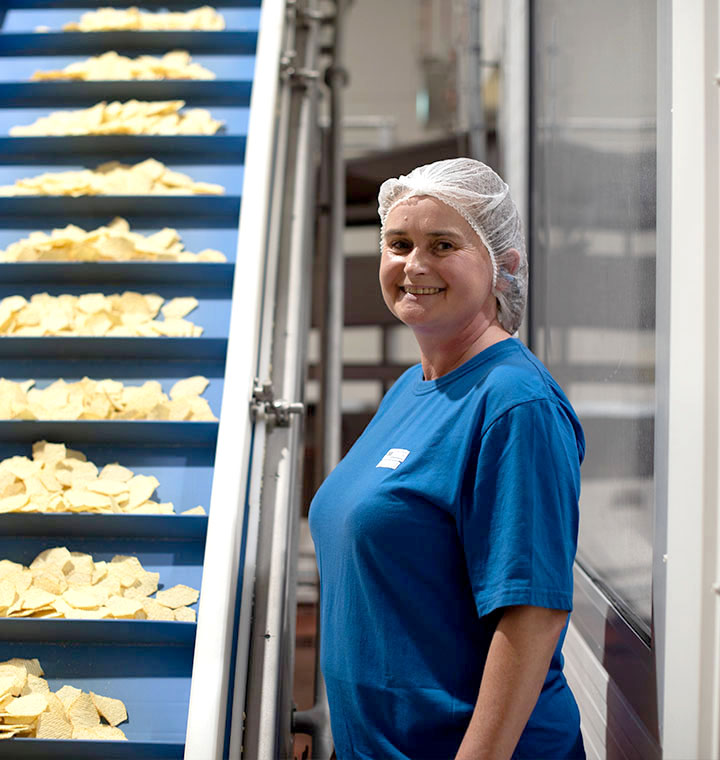 Associate smiling next to chip conveyor belt